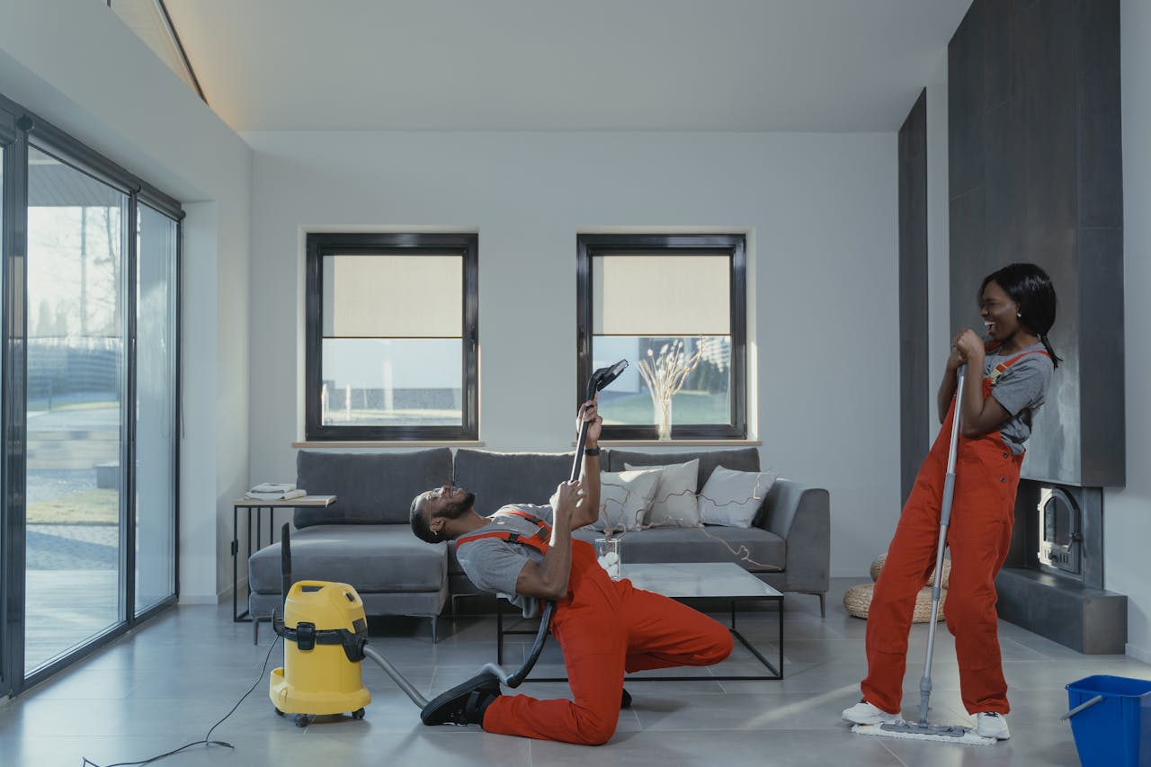 about-02 Fun and engaging cleaning session with a man and woman in overalls using cleaning tools in a modern living room.